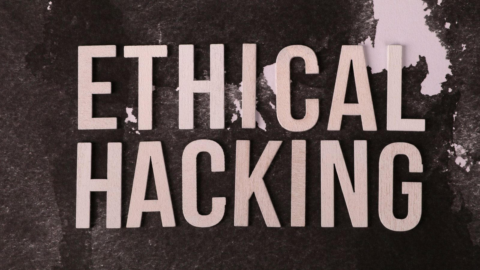 Wooden letters spelling "Ethical Hacking" on dark textured paper