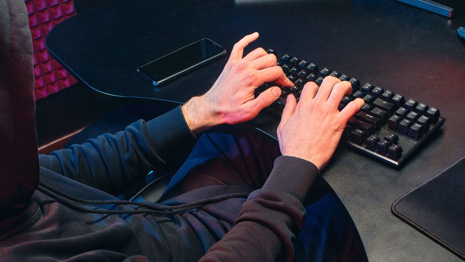 Hands typing at a keyboard below a monitor showing system output